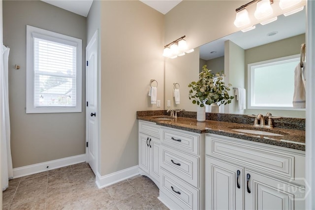 full bath featuring baseboards and double vanity