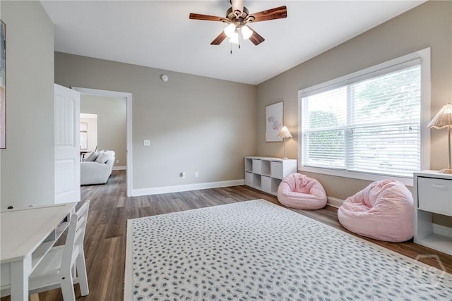 living area with ceiling fan, baseboards, and dark wood-type flooring