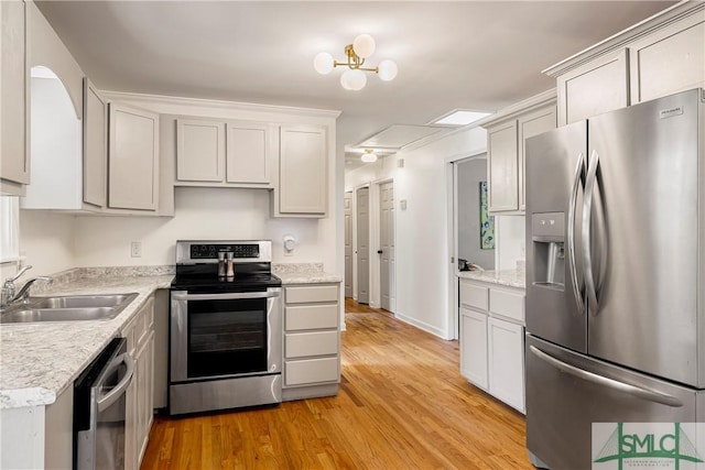 kitchen with appliances with stainless steel finishes, a sink, light wood-style flooring, and light countertops