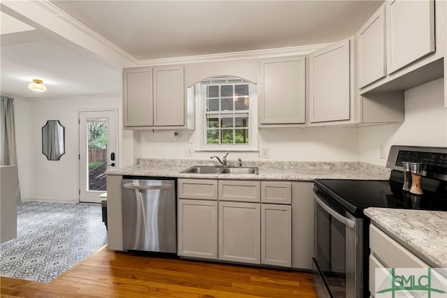 kitchen with appliances with stainless steel finishes, a sink, dark wood-type flooring, light countertops, and crown molding