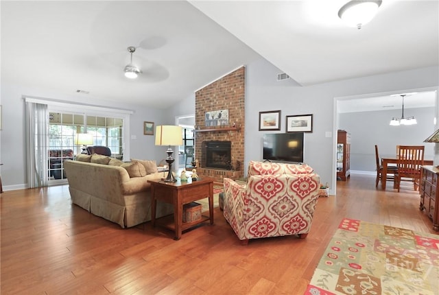 6 Ramsgate Rd, Savannah, GA 31419 - living room with vaulted ceiling, a ceiling fan, light wood-type flooring, a brick fireplace, and a chandelier