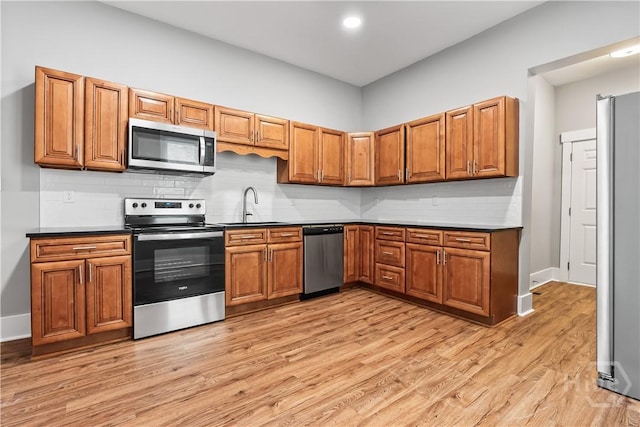 523 E 39th St, Savannah, GA 31401 - kitchen featuring appliances with stainless steel finishes, a sink, brown cabinetry, light wood-style flooring, and recessed lighting