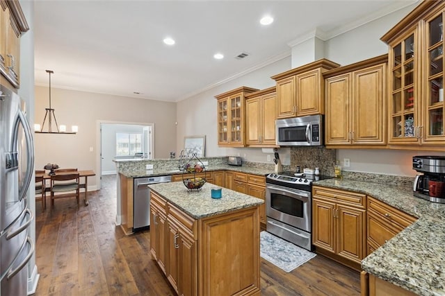 kitchen featuring stainless steel appliances, a peninsula, brown cabinets, a chandelier, and light stone counters