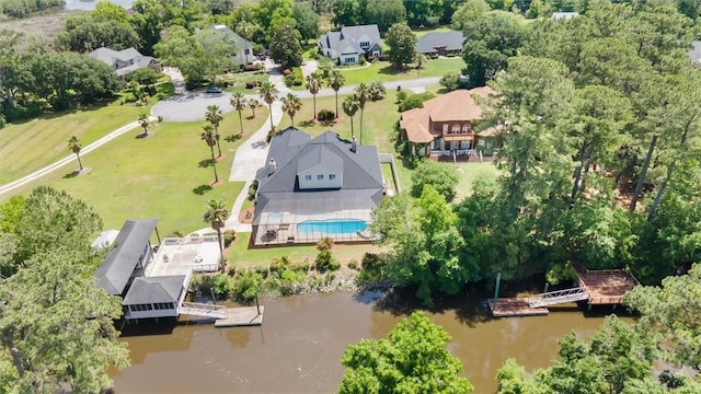 aerial perspective of suburban area with a nearby body of water, a pool, and a tree filled landscape