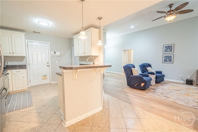kitchen with open floor plan, a kitchen breakfast bar, a peninsula, a ceiling fan, and white cabinetry
