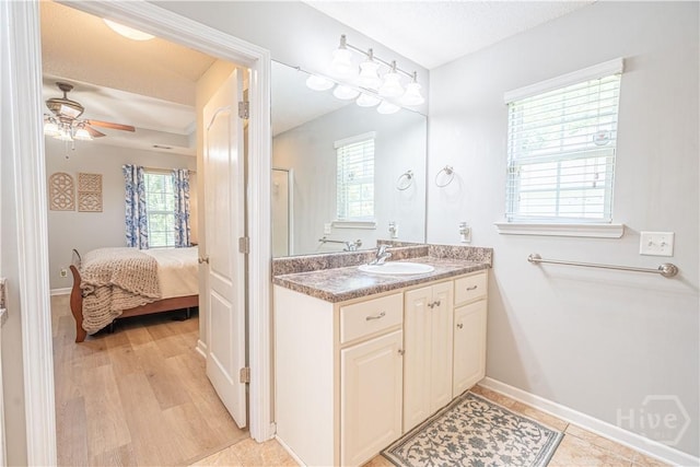 bathroom with ceiling fan, connected bathroom, baseboards, and vanity