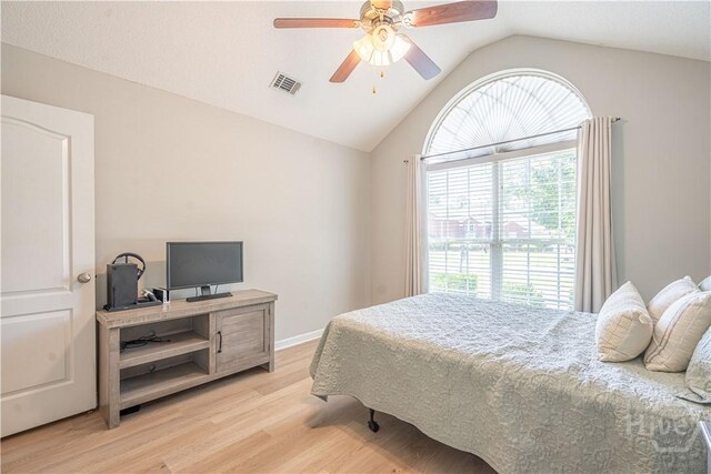 bedroom featuring lofted ceiling, multiple windows, light wood-style floors, an office area, and a ceiling fan