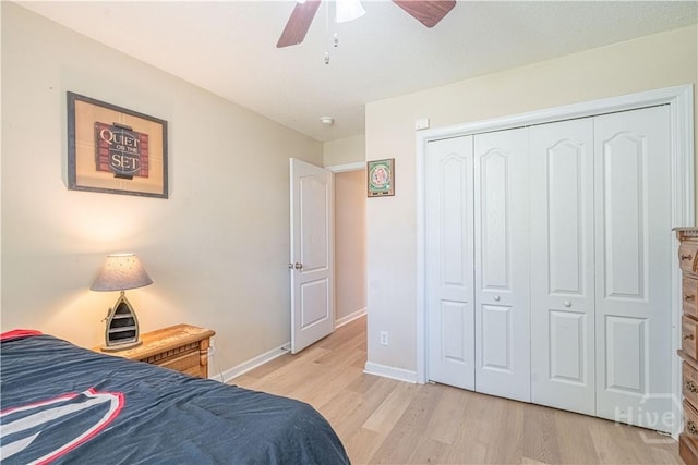 bedroom featuring light wood-style flooring, baseboards, a closet, and ceiling fan