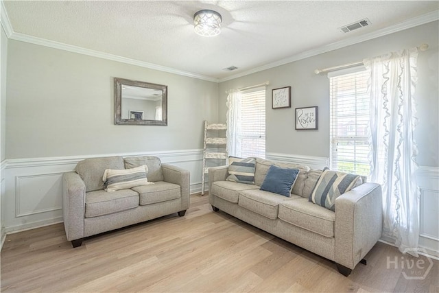 living room featuring wainscoting, light wood-style floors, and ornamental molding