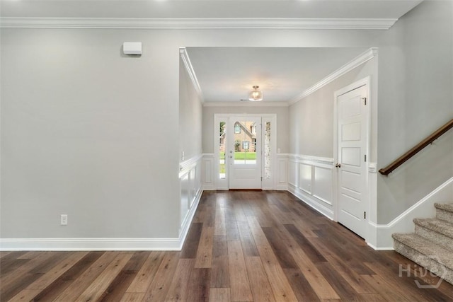 foyer entrance featuring stairs, dark wood-style floors, crown molding, and a wainscoted wall
