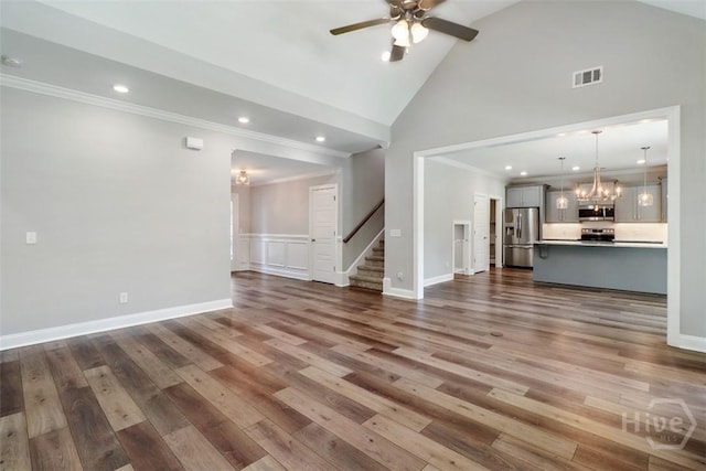 unfurnished living room featuring stairs, crown molding, a chandelier, a ceiling fan, and dark wood-type flooring