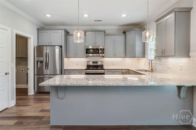 kitchen featuring appliances with stainless steel finishes, gray cabinetry, a sink, light stone counters, and ornamental molding