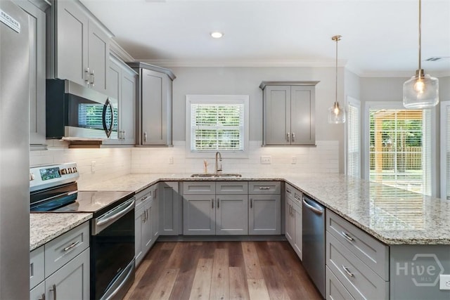 kitchen featuring appliances with stainless steel finishes, a sink, gray cabinets, a peninsula, and crown molding