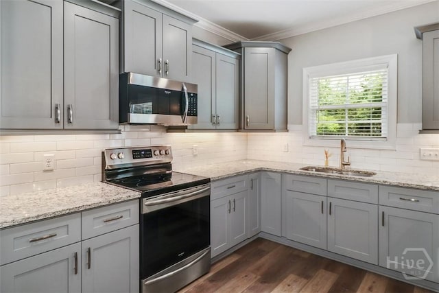 kitchen featuring stainless steel appliances, a sink, gray cabinets, ornamental molding, and backsplash