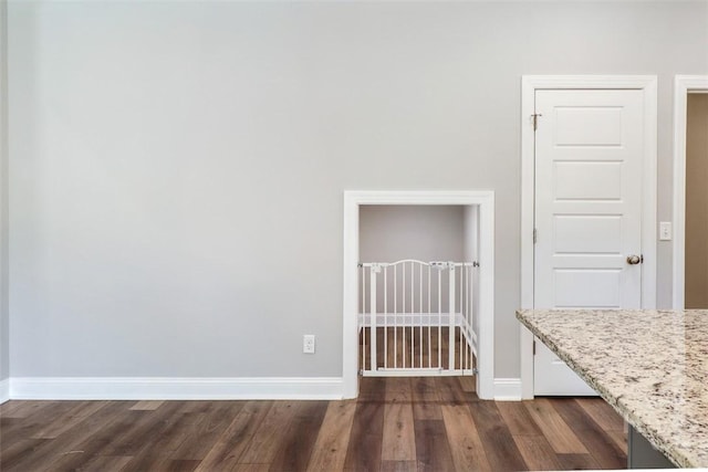spare room with dark wood-style flooring and baseboards