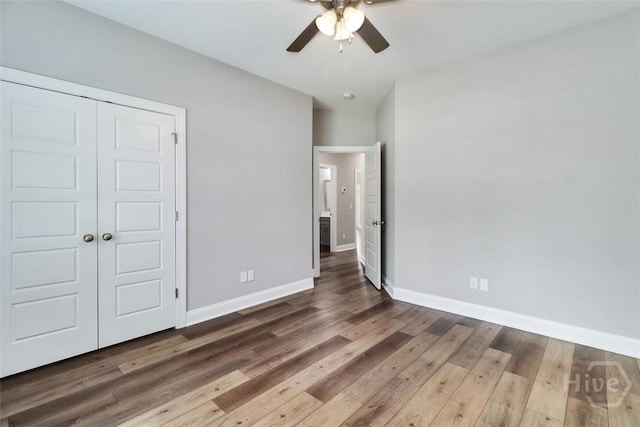 unfurnished bedroom featuring baseboards, hardwood / wood-style flooring, a closet, and ceiling fan