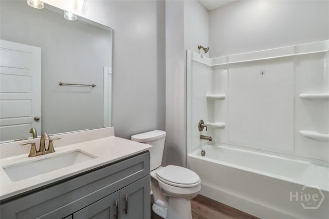 bathroom featuring wood finished floors, toilet, bathing tub / shower combination, and vanity