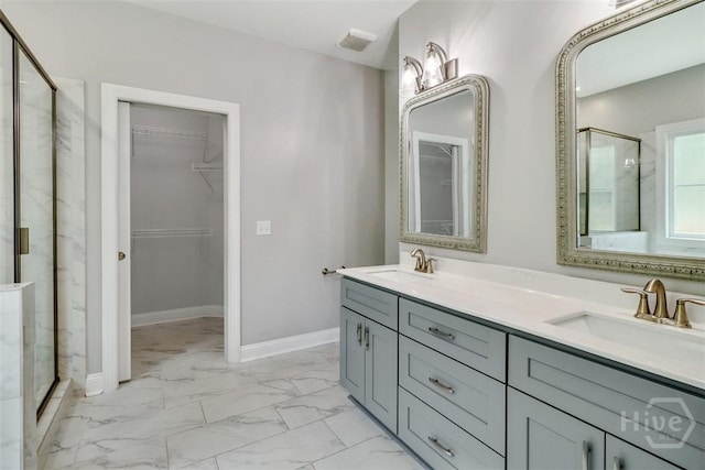 bathroom with marble finish floors, a shower stall, a walk in closet, and double vanity