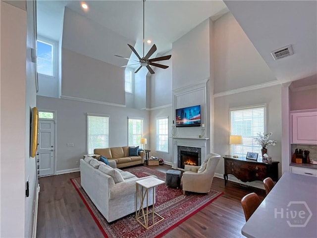 living area with high vaulted ceiling, a premium fireplace, dark wood finished floors, a ceiling fan, and baseboards