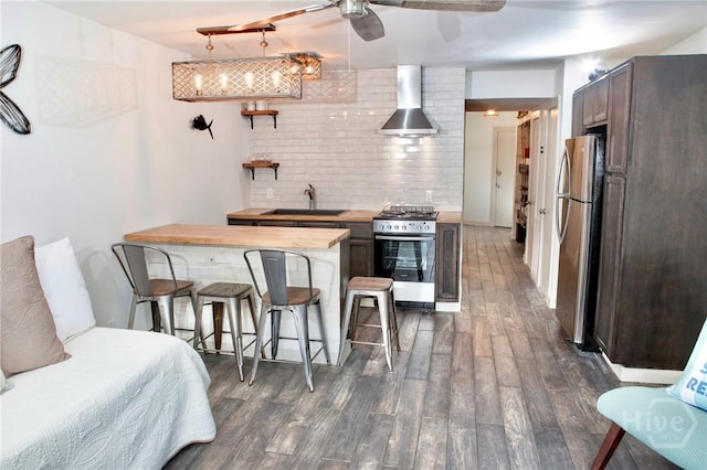 1217 Bay St Unit 131A, Tybee Island, GA 31328 - kitchen featuring stainless steel appliances, dark wood-type flooring, a breakfast bar area, wall chimney range hood, and a peninsula