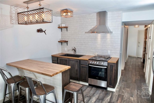 1217 Bay St Unit 131A, Tybee Island, GA 31328 - kitchen featuring butcher block counters, wall chimney exhaust hood, stainless steel range oven, and a breakfast bar
