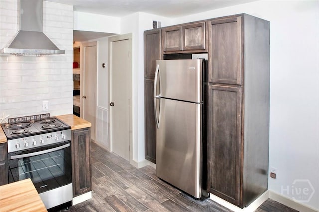 1217 Bay St Unit 131A, Tybee Island, GA 31328 - kitchen with appliances with stainless steel finishes, wall chimney range hood, decorative backsplash, dark brown cabinets, and dark wood-style flooring