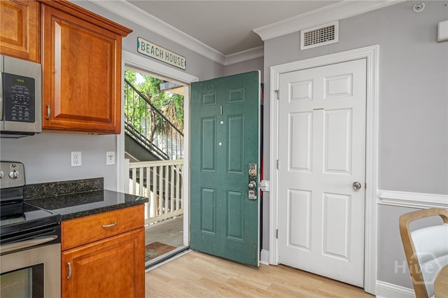 18 Silver Ave Unit 1, Tybee Island, GA 31328 - kitchen featuring stainless steel appliances, light wood finished floors, crown molding, brown cabinets, and dark stone counters