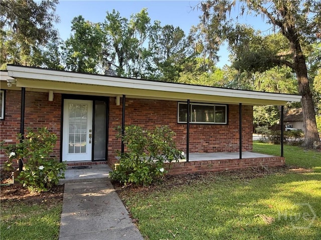view of front of house featuring a front yard, brick siding, and a porch