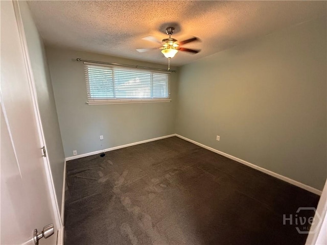 unfurnished room featuring ceiling fan, a textured ceiling, dark colored carpet, and baseboards