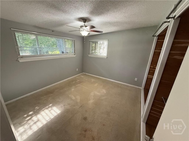 unfurnished bedroom with a textured ceiling, carpet floors, baseboards, and ceiling fan