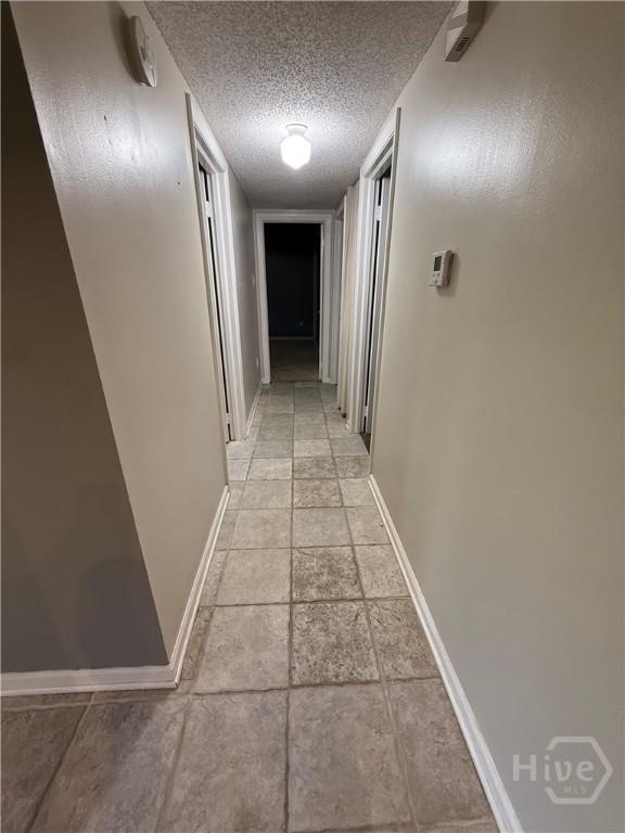 corridor with baseboards and a textured ceiling