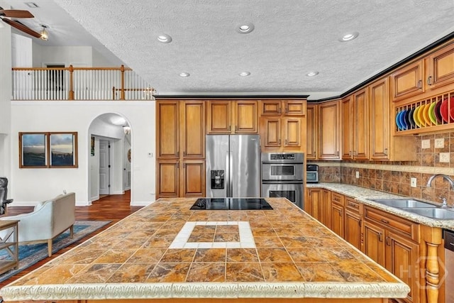 473 Kolic Helmey Rd, Guyton, GA 31312 - kitchen with stainless steel appliances, a sink, a center island, arched walkways, and brown cabinets