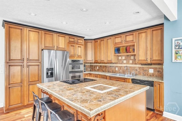 473 Kolic Helmey Rd, Guyton, GA 31312 - kitchen with stainless steel appliances, a sink, a center island, light countertops, and light wood-style flooring
