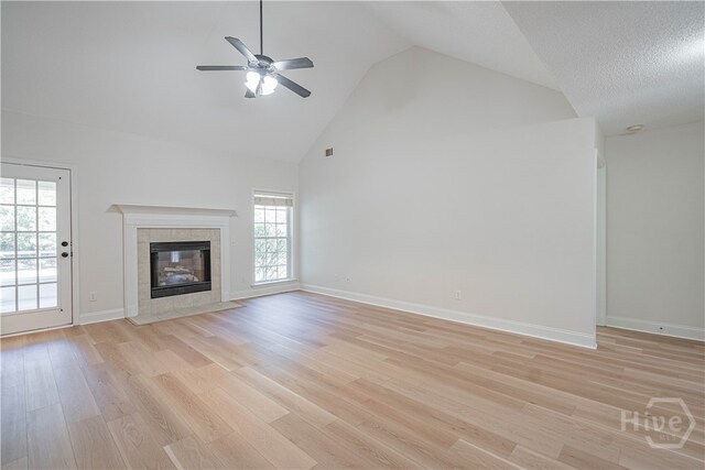 110 Pembroke Pl, Pembroke, GA 31321 - unfurnished living room with high vaulted ceiling, a tiled fireplace, ceiling fan, light wood finished floors, and baseboards
