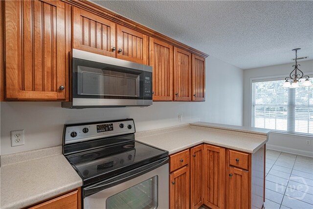 110 Pembroke Pl, Pembroke, GA 31321 - kitchen featuring appliances with stainless steel finishes, brown cabinets, light tile patterned floors, a peninsula, and a textured ceiling