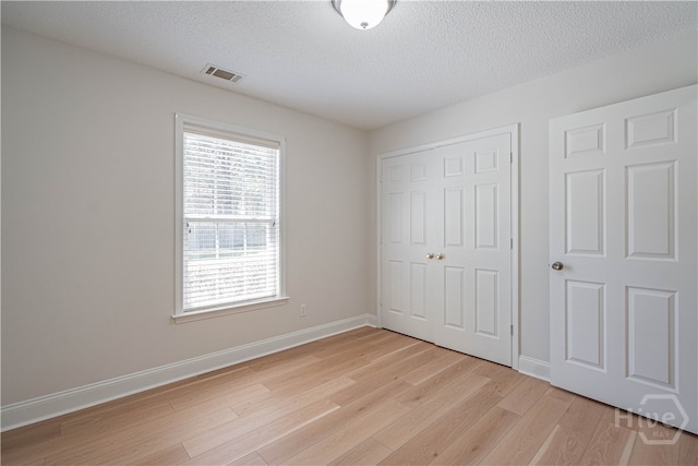 110 Pembroke Pl, Pembroke, GA 31321 - unfurnished bedroom featuring light wood finished floors, a closet, a textured ceiling, and baseboards