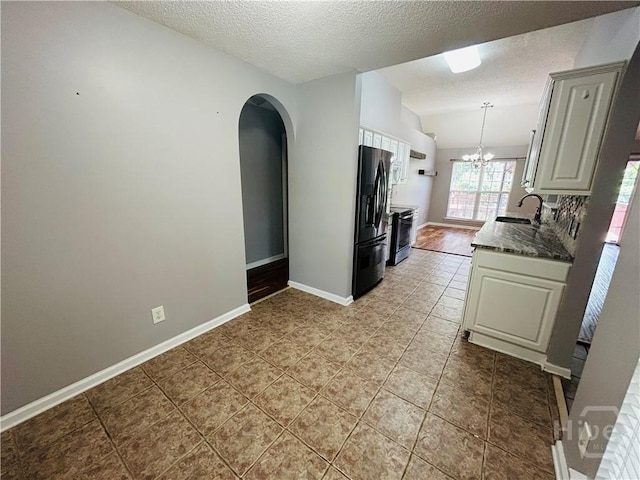 152 Junco Way, Savannah, GA 31419 - kitchen with black fridge, arched walkways, a sink, lofted ceiling, and a textured ceiling