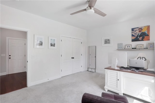 home office with light carpet, a ceiling fan, and baseboards
