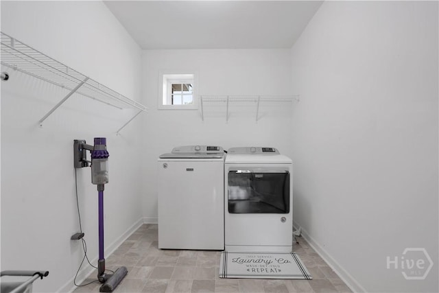 clothes washing area featuring separate washer and dryer and baseboards