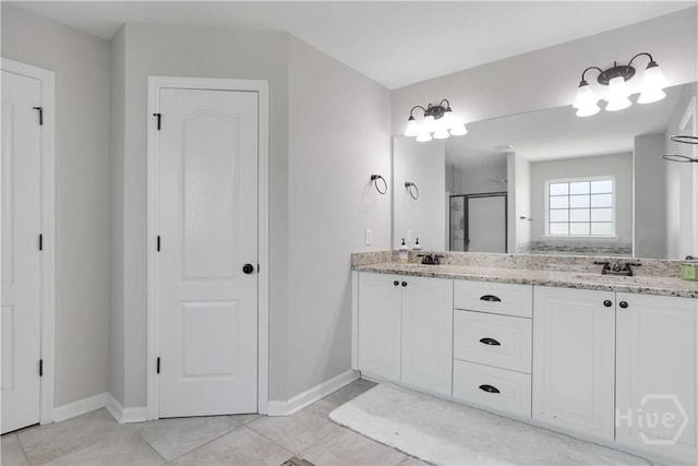 full bath with a stall shower, baseboards, and double vanity