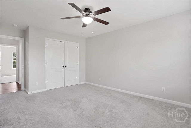 unfurnished bedroom featuring carpet flooring, baseboards, a closet, and ceiling fan