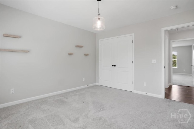 unfurnished bedroom featuring carpet flooring, baseboards, attic access, and a closet