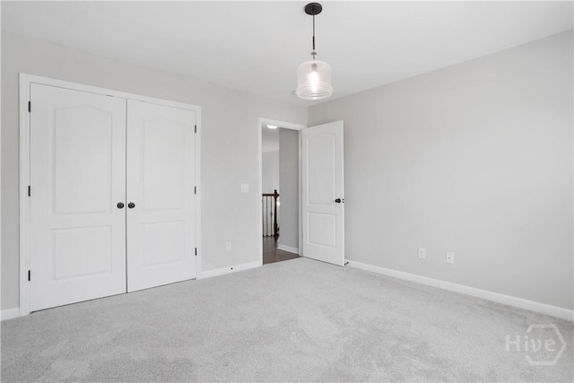 unfurnished bedroom featuring carpet flooring, baseboards, and a closet