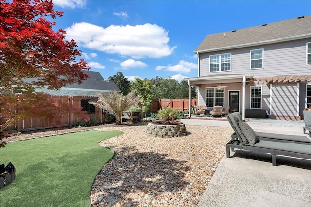 rear view of house with a fenced backyard, a patio area, a ceiling fan, and an outdoor living space with a fire pit