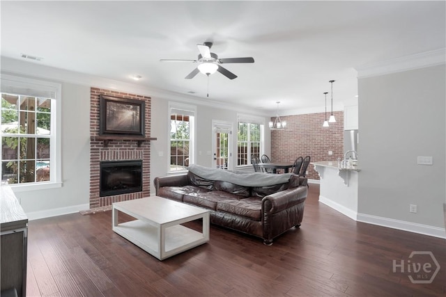living room featuring a ceiling fan, baseboards, a fireplace, dark wood-style flooring, and crown molding