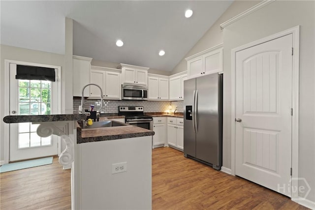 306 Madison Oaks Dr, Rincon, GA 31326 - kitchen with appliances with stainless steel finishes, a peninsula, a sink, white cabinetry, and vaulted ceiling