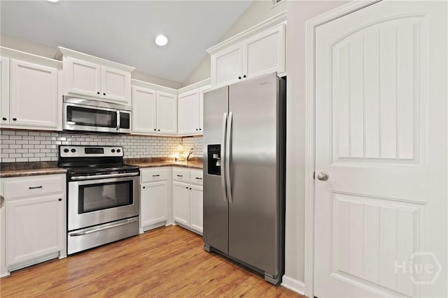 306 Madison Oaks Dr, Rincon, GA 31326 - kitchen featuring appliances with stainless steel finishes, dark countertops, white cabinetry, backsplash, and lofted ceiling