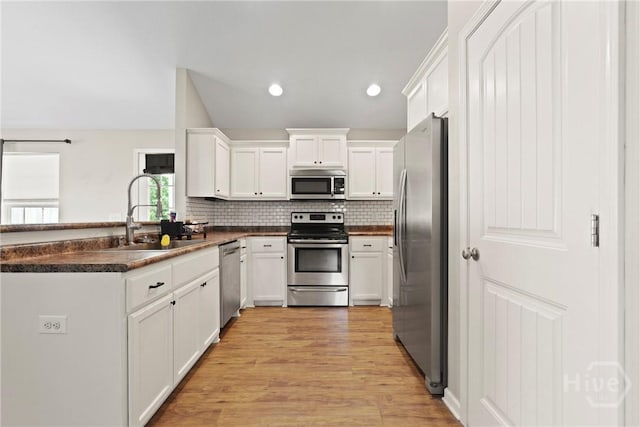 306 Madison Oaks Dr, Rincon, GA 31326 - kitchen with appliances with stainless steel finishes, a sink, dark countertops, white cabinetry, and light wood-style flooring