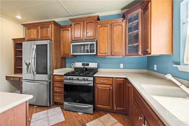 303 Stonebridge Cir, Savannah, GA 31419 - kitchen featuring stainless steel appliances, light countertops, light wood-type flooring, glass insert cabinets, and brown cabinets