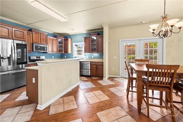 303 Stonebridge Cir, Savannah, GA 31419 - kitchen featuring appliances with stainless steel finishes, glass insert cabinets, a chandelier, plenty of natural light, and crown molding